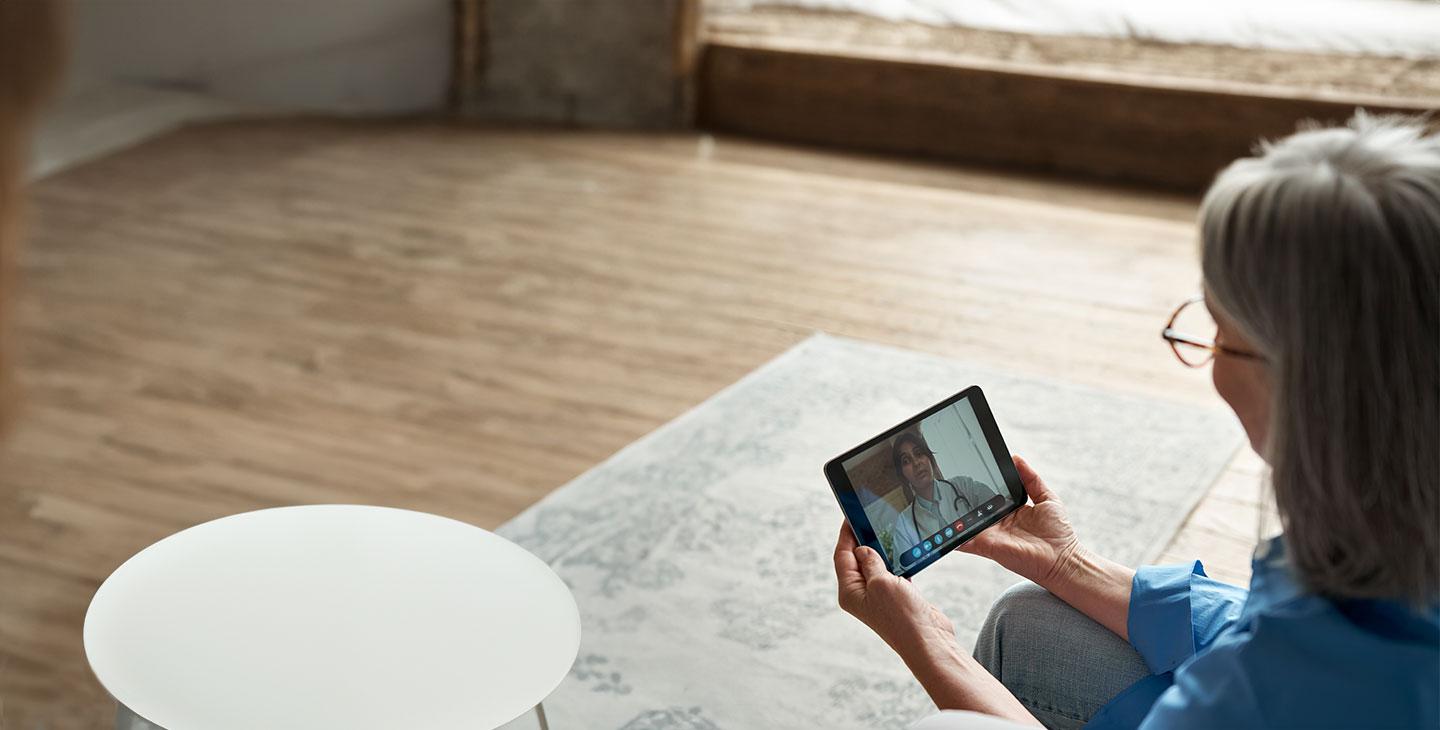 a woman using a tablet for a tele健康 appointment, connected by Viasat satellite internet